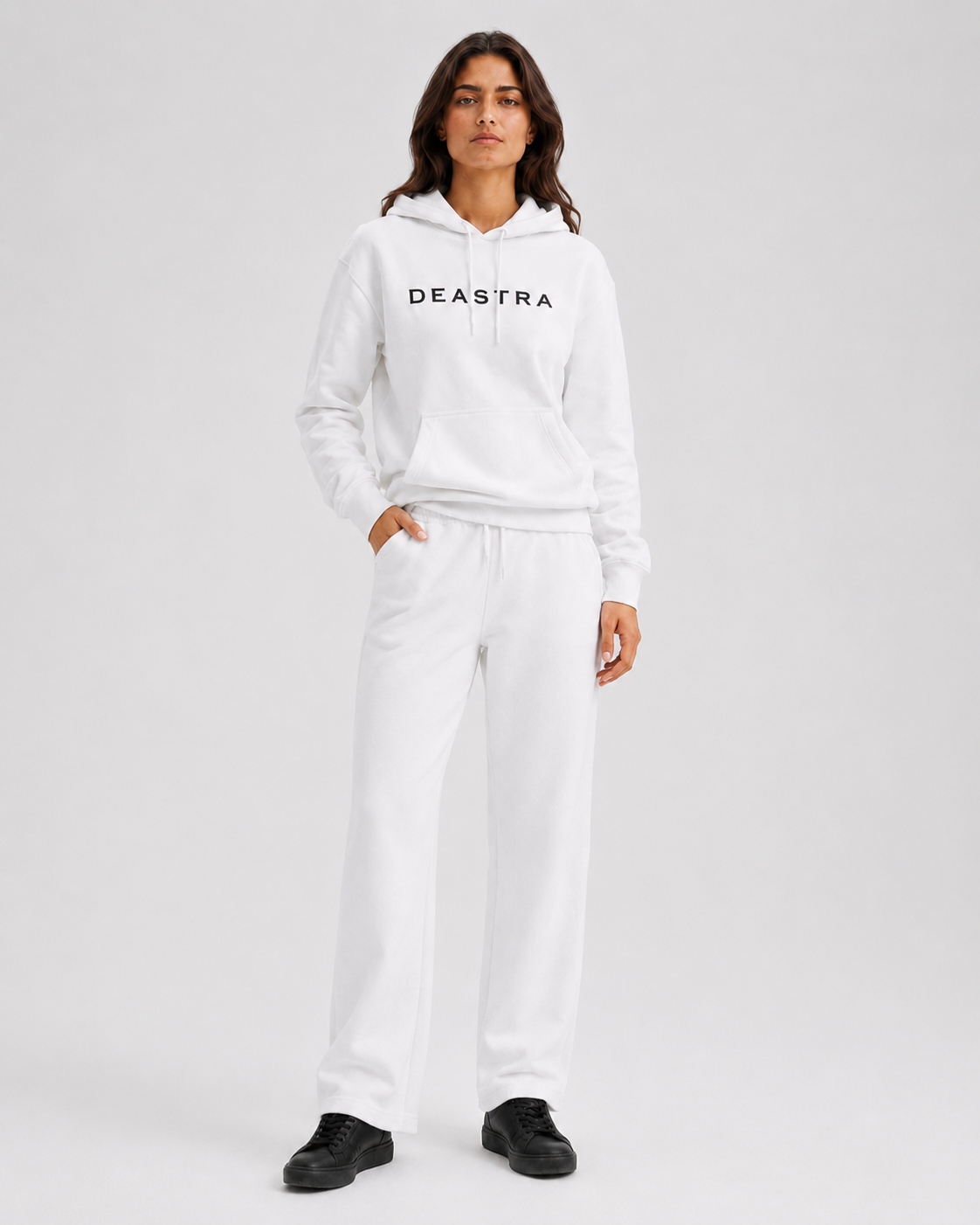Person wearing a white hoodie and pants with 'DEASTRA' branding on a light gray background