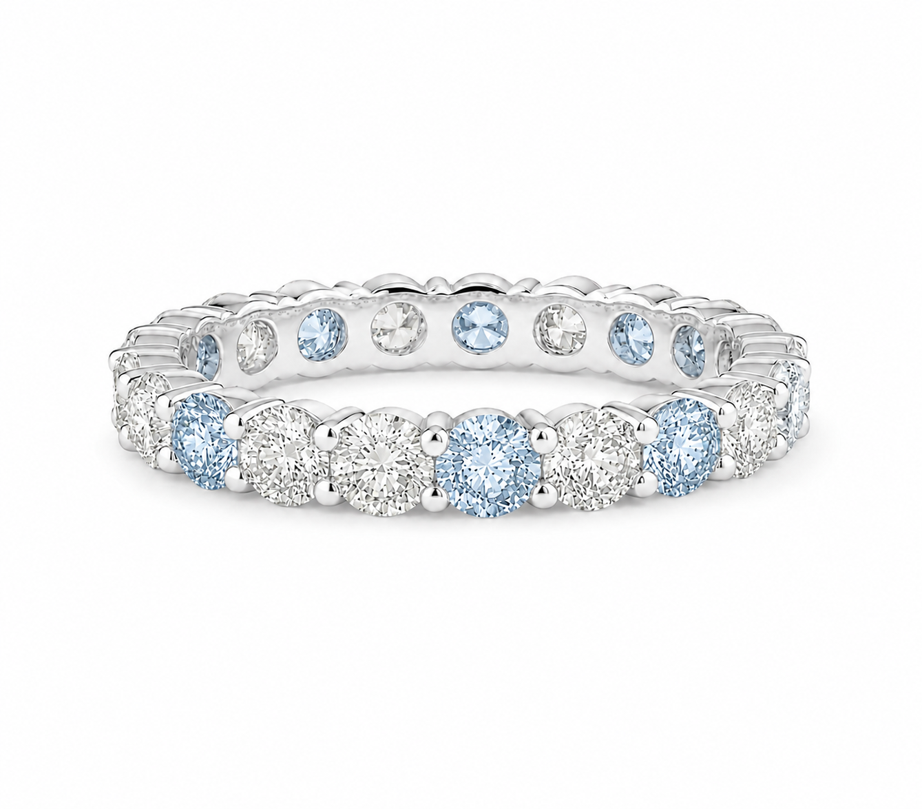 A silver eternity ring featuring round-cut light blue sapphires and clear round diamonds, shown on a clean white background.