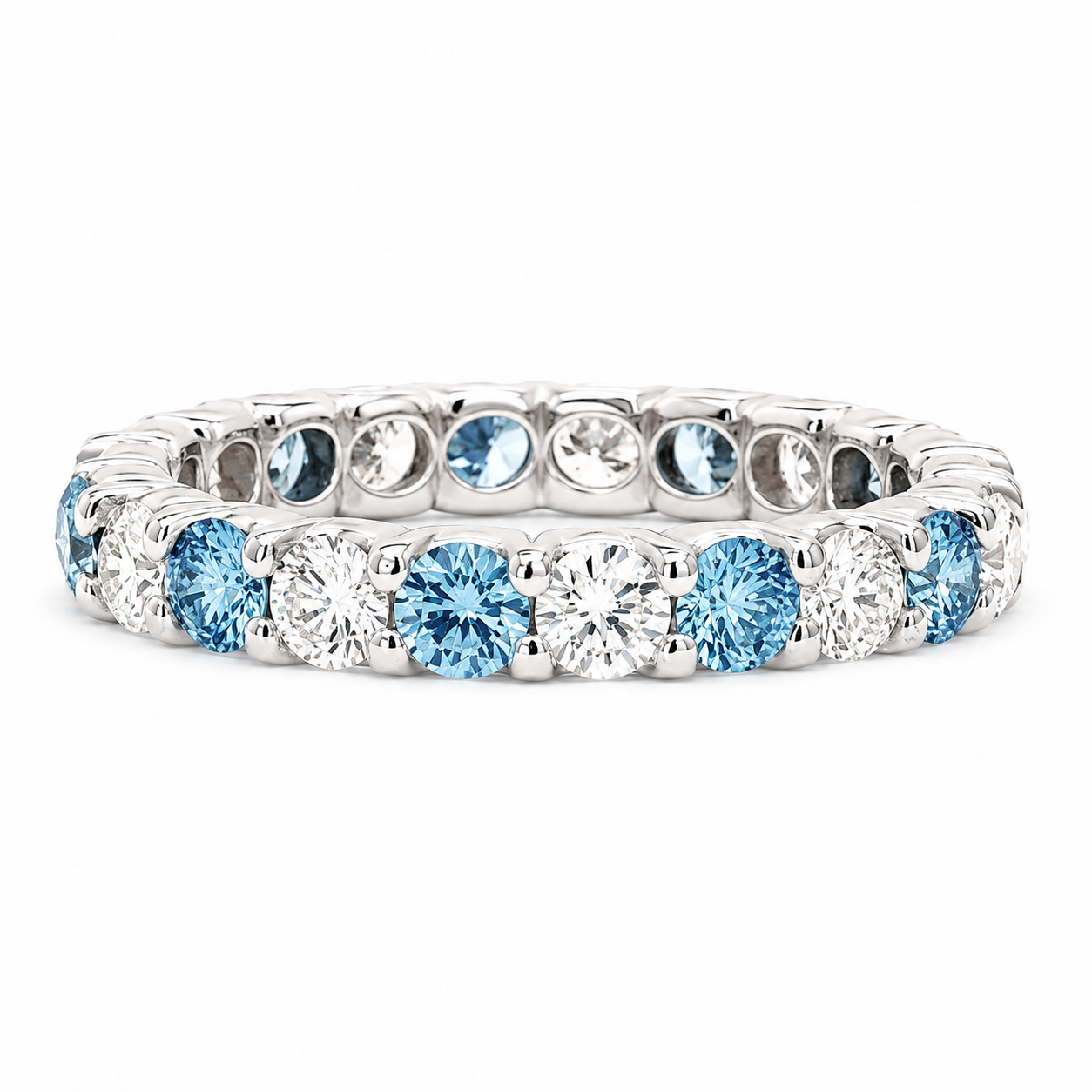 A silver-toned eternity ring featuring alternating round-cut light blue topaz and clear round diamonds, set against a plain white background.