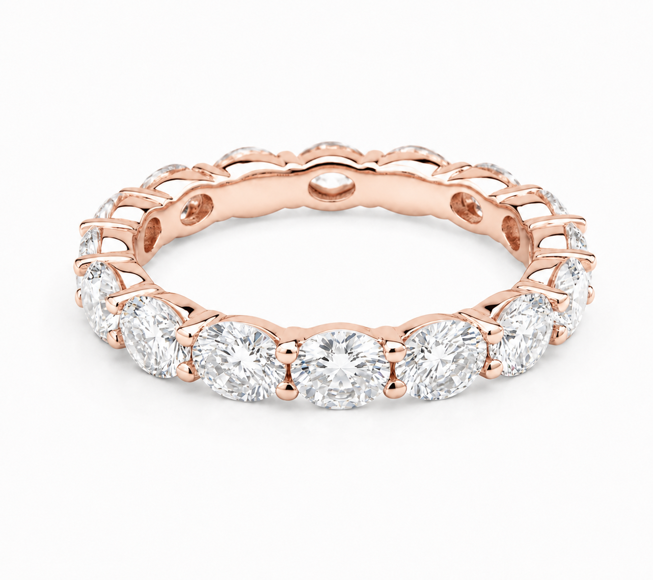 A rose gold eternity ring featuring a continuous row of round brilliant-cut diamonds in a prong setting, shown on a clean white background.