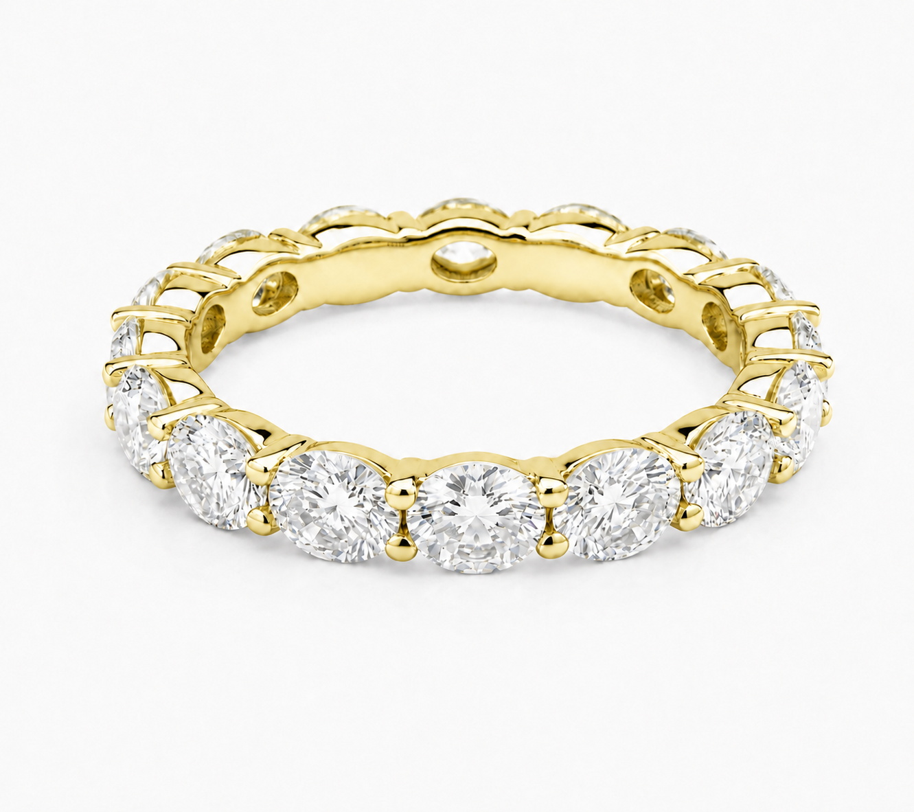 A yellow gold eternity ring featuring a continuous row of round-cut clear gemstones in a prong setting, shown on a clean white background.