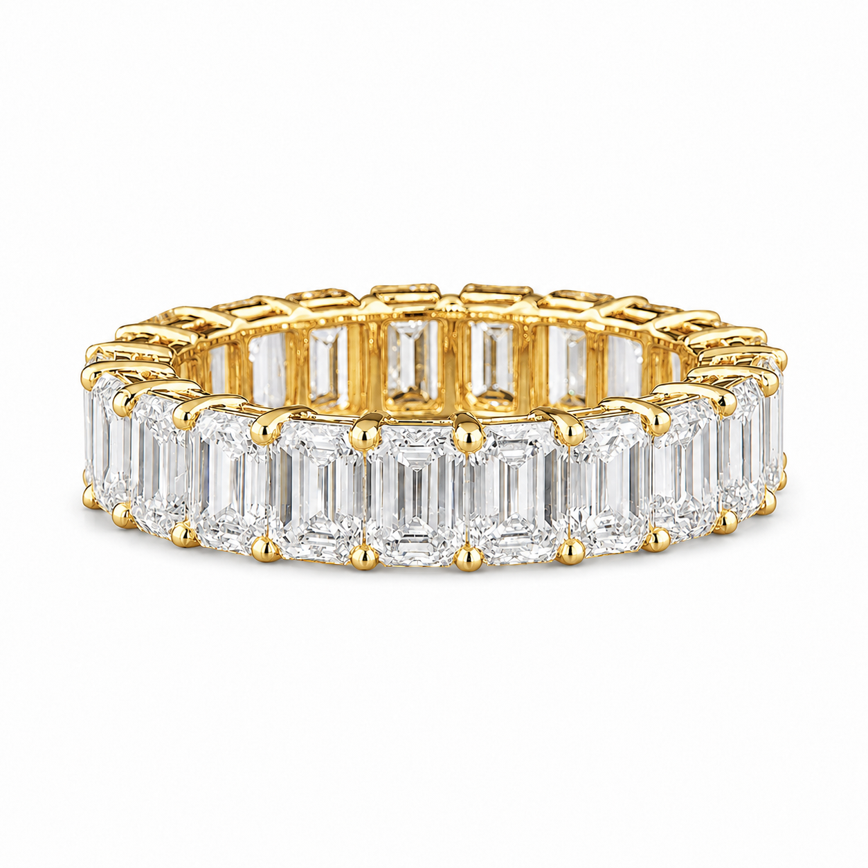 A yellow gold eternity ring featuring a continuous row of baguette-cut clear gemstones on the front half and round stones on the back, set against a plain white background.