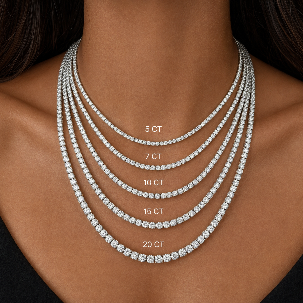 A close-up of a model's neck and upper chest wearing five layered diamond tennis necklaces of different carat counts: 5 CT, 7 CT, 10 CT, 15 CT, and 20 CT, labeled in white text.