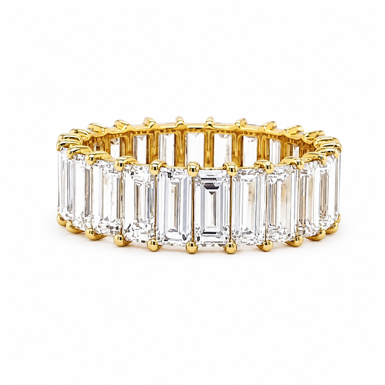A yellow gold eternity ring featuring a continuous row of clear baguette-cut gemstones, photographed on a seamless white background.